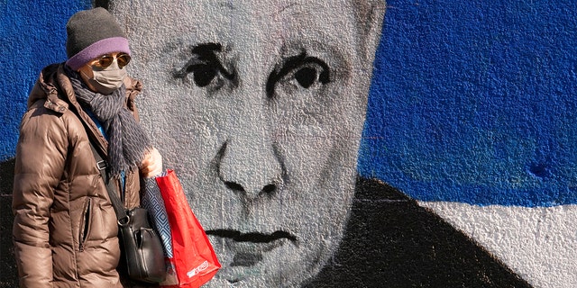 امرأة تمر بجانب جدارية تصور الرئيس الروسي فلاديمير بوتين في بلغراد ، صربيا ، السبت 12 مارس 2022. 