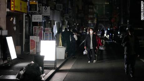 الناس يسيرون في أحد الشوارع أثناء انقطاع التيار الكهربائي في طوكيو.