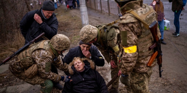 جنود أوكرانيون يرعون امرأة شبه واعية بعد عبور نهر إيربين أثناء الفرار من المدينة في ضواحي كييف بأوكرانيا ، يوم السبت 5 مارس 2022. 