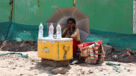 فتاة تبيع الماء تستخدم مظلة لحماية نفسها من أشعة الشمس في نيودلهي.