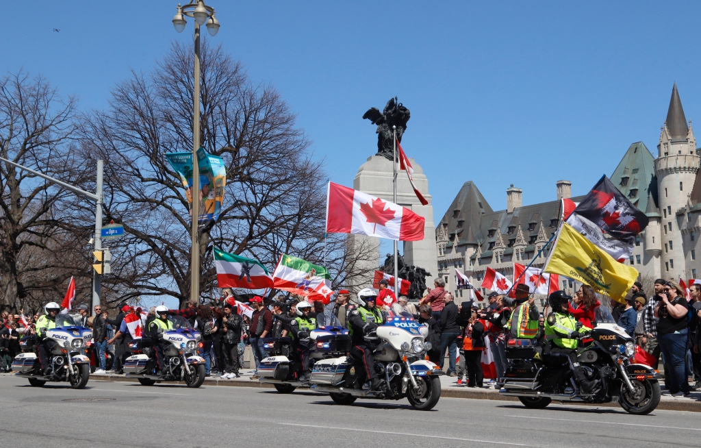 رجال شرطة على دراجات نارية يمرون بمظاهرة ، ويدعو جزء من مظاهرة على غرار قافلة "الرعد المتداول" في أوتاوا ، أونتاريو ، يوم السبت 30 أبريل 2022.