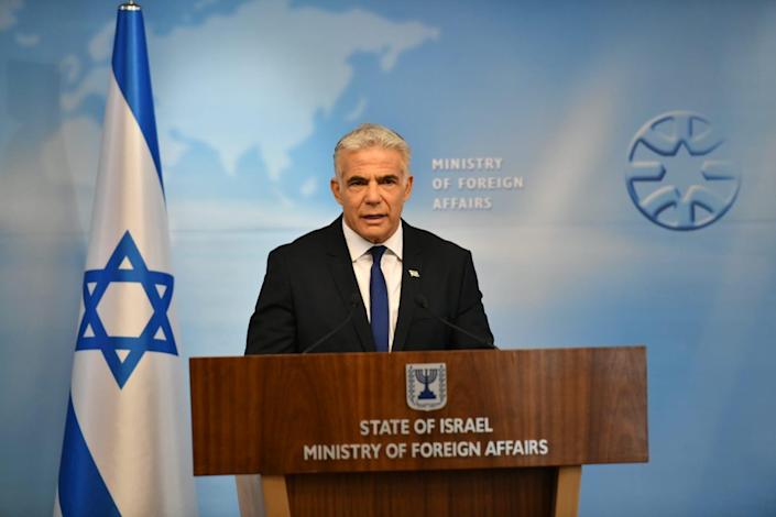 وزير الخارجية الإسرائيلي يائير لبيد على منصة بجانب العلم الإسرائيلي ، وخلفه طبعت وزارة الخارجية على الحائط.