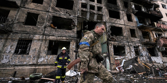 جنود ورجال إطفاء أوكرانيون يبحثون في مبنى مدمر بعد هجوم بالقنابل في كييف ، أوكرانيا ، الإثنين 14 مارس 2022 (AP Photo / Vadim Ghirda)