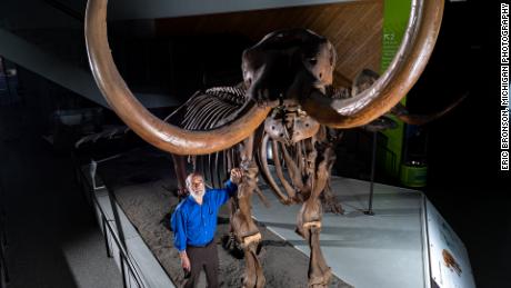 يقف عالم الأحافير بجامعة ميتشيغان دانييل فيشر مع هيكل عظمي مُركب من حيوان المستودون Buesching.