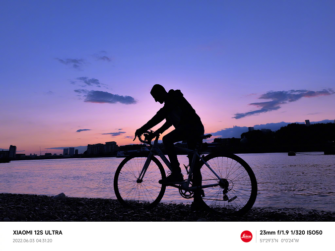 لقطة عينة تم التقاطها باستخدام هاتف Xiaomi 12S Ultra ، يظهر فيها راكب دراجة على ضفة نهر في الصباح الباكر قبل شروق الشمس.