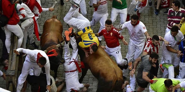 العداؤون يسقطون ويضربون من مصارعة الثيران أثناء سباق الثيران في مهرجان سان فيرمين في بامبلونا ، إسبانيا ، يوم الاثنين ، 11 يوليو ، 2022.