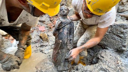 اثنان من علماء الآثار يحملان تمثالًا لصبي.
