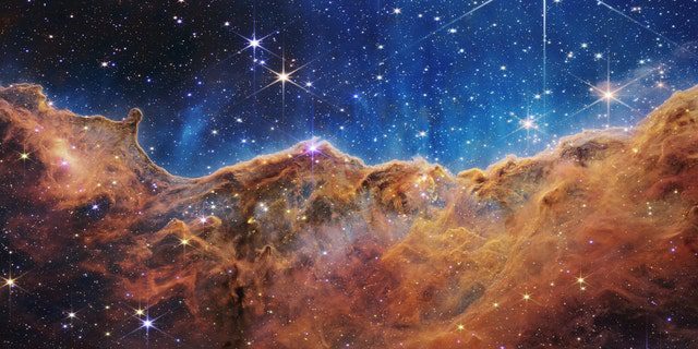 ما يشبه إلى حد كبير الجبال الصخرية في أمسية مقمرة هو في الواقع حافة منطقة تشكل النجوم القريبة والشابة NGC 3324 في سديم كارينا.  تم التقاط هذه الصورة في ضوء الأشعة تحت الحمراء بواسطة كاميرا الأشعة تحت الحمراء القريبة (NIRCam) على تلسكوب جيمس ويب الفضائي التابع لناسا ، وتكشف عن مناطق كانت محجوبة من قبل لولادة النجوم.